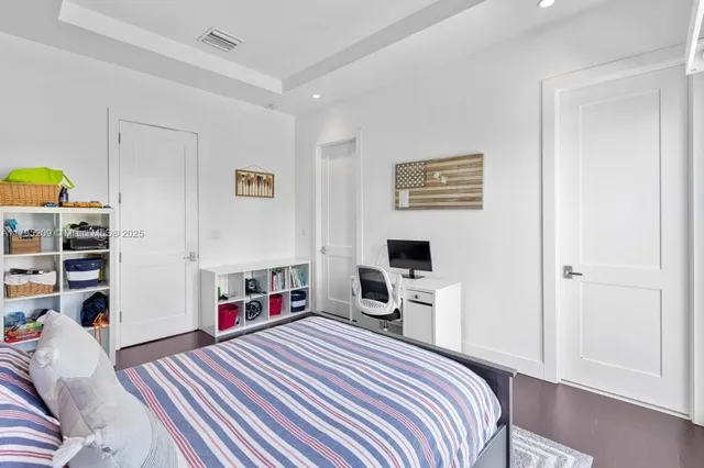 a bedroom with a bed and a flat tv screen on the dresser