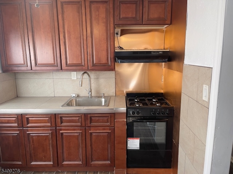 1112 Rivington Street Roselle, NJ 07203 - Photo 4 of 13 a kitchen with stainless steel appliances granite countertop a stove a sink and a refrigerator with wooden cabinets