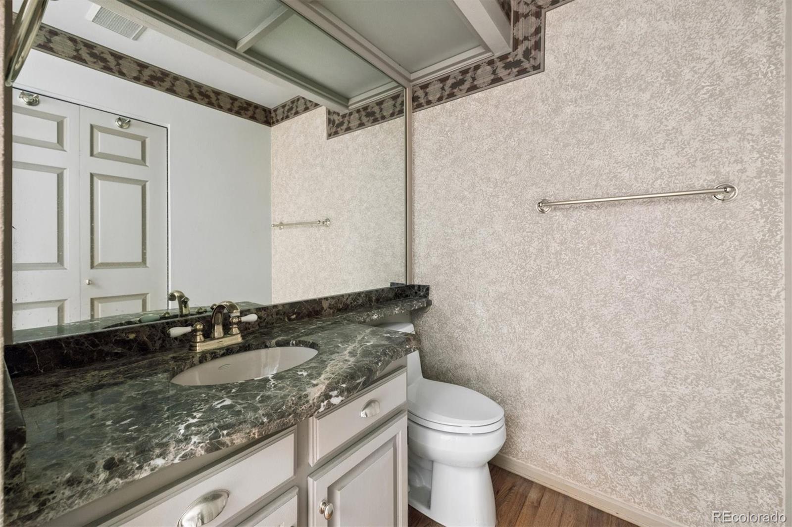 8554 Redstone Street Highlands Ranch, CO 80126 - Photo 16 of 33 a bathroom with a granite countertop sink a toilet and a mirror