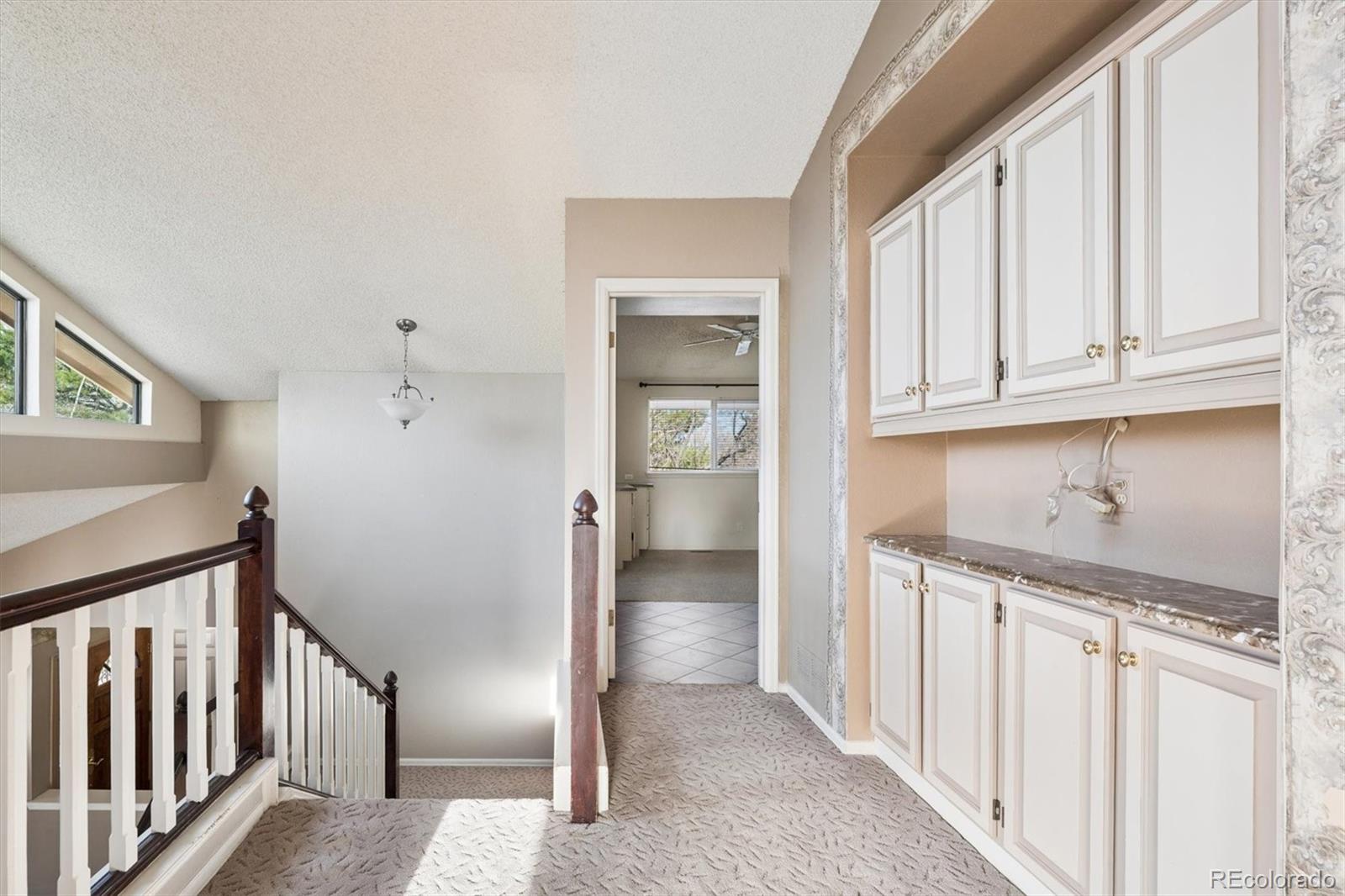 8554 Redstone Street Highlands Ranch, CO 80126 - Photo 18 of 33 a view of hallway with granite countertop wooden cabinets and entryway