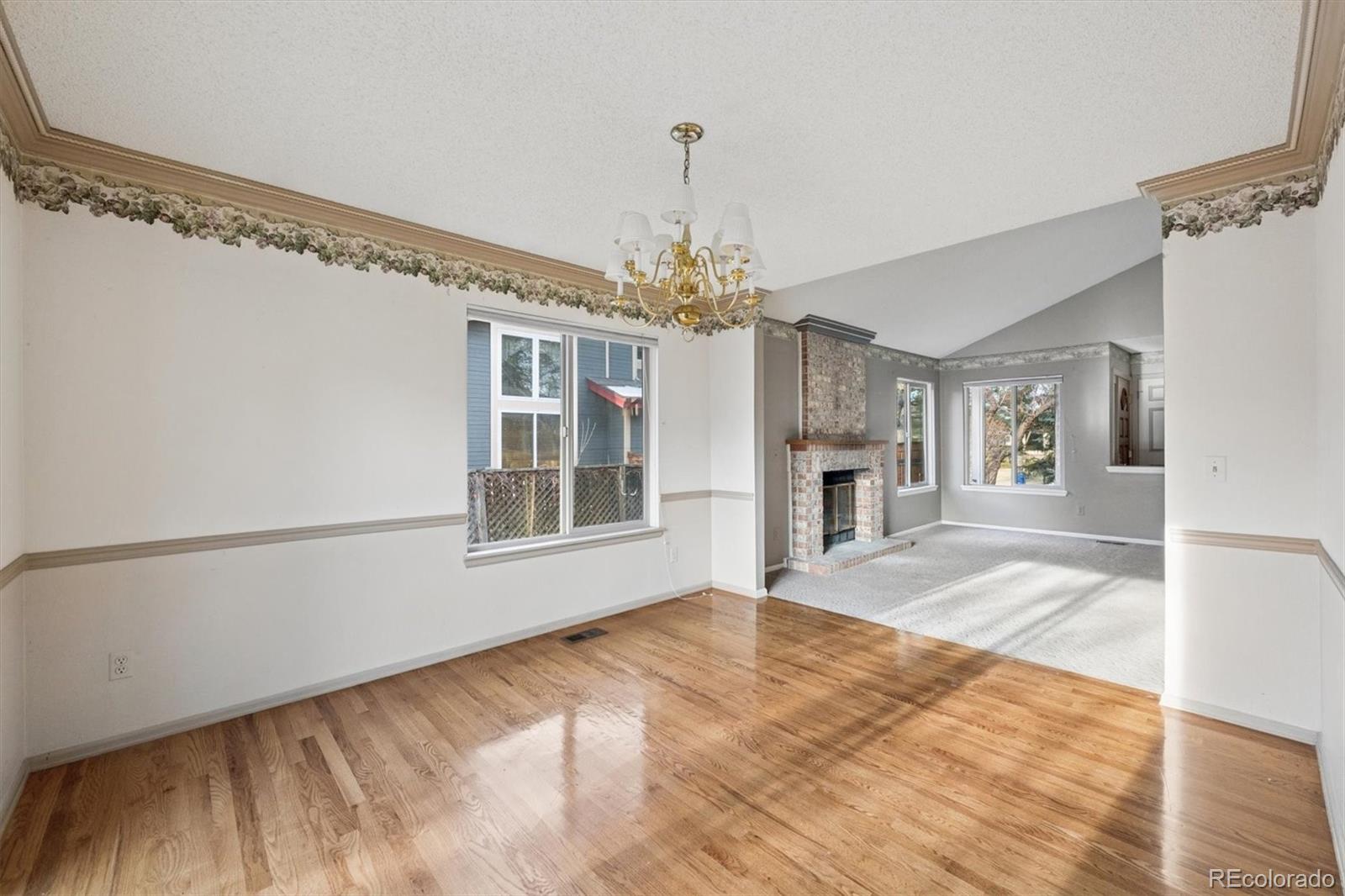 8554 Redstone Street Highlands Ranch, CO 80126 - Photo 9 of 33 a view of an empty room with chandelier and wooden floor