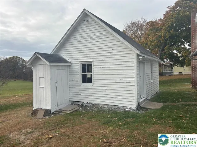 a view of a small space in front of a house with a large tree