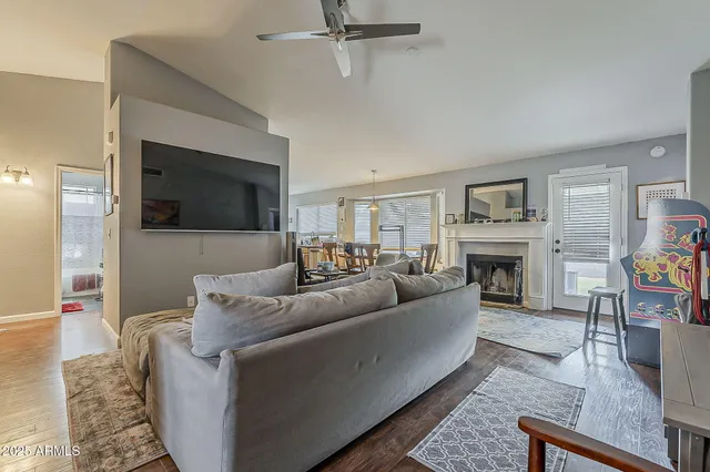 a living room with furniture kitchen view and a wooden floor