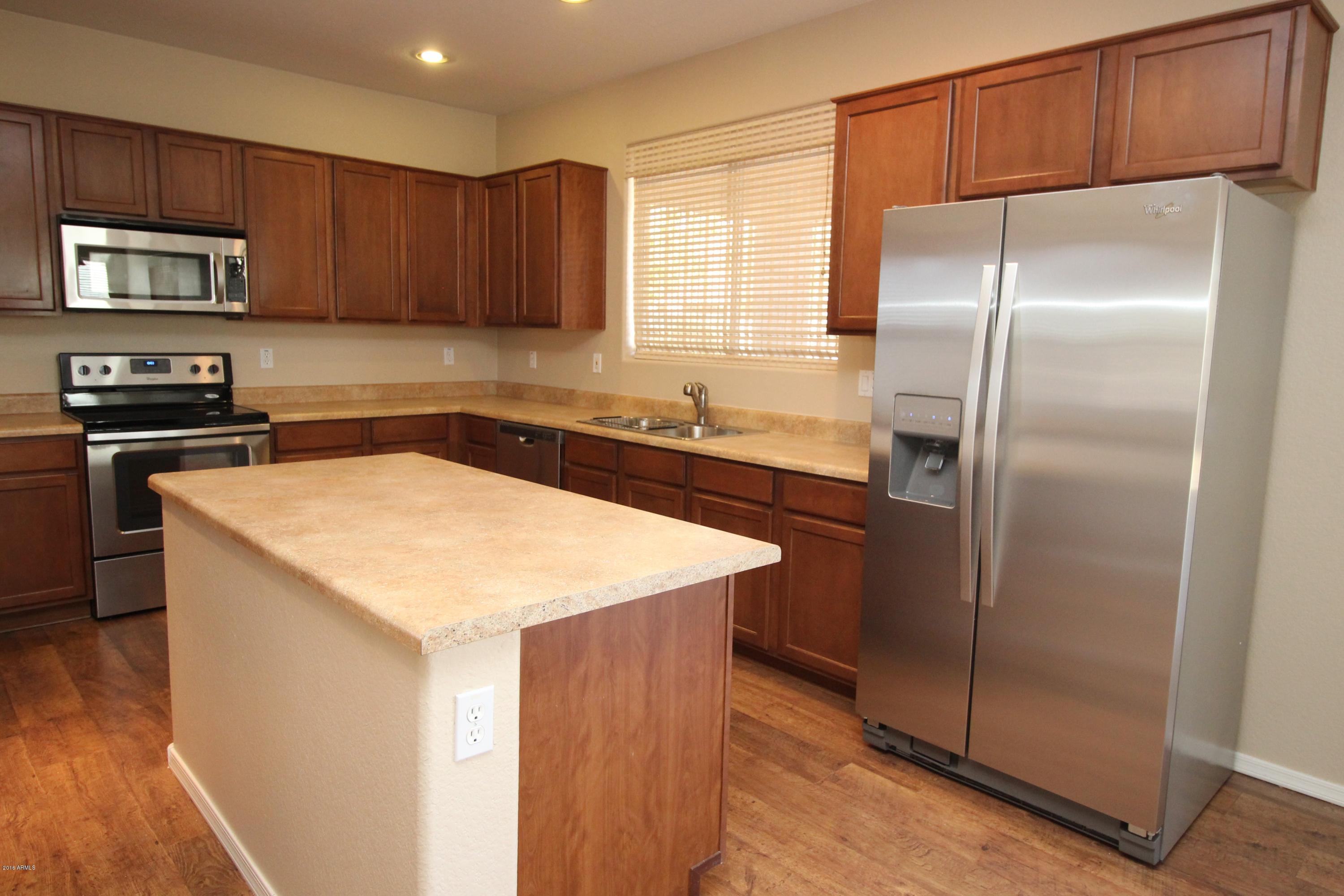 45774 West Ranch Road Maricopa, AZ 85139 - Photo 7 of 25 a kitchen with a refrigerator a microwave a sink and cabinets