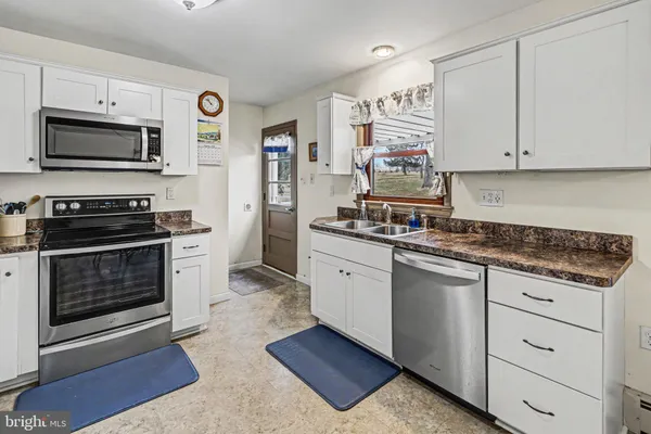 a kitchen with granite countertop white cabinets and stainless steel appliances