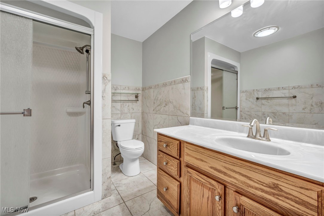503 Churchill Road Youngstown, OH 44505 - Photo 9 of 32 Bathroom with tile walls, vanity, a stall shower, wainscoting, and light tile patterned floors