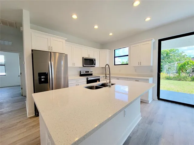 a kitchen with stainless steel appliances a refrigerator sink and wooden floor