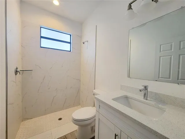 a bathroom with a granite countertop sink a toilet and shower