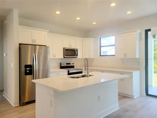a kitchen with stainless steel appliances a refrigerator sink and microwave