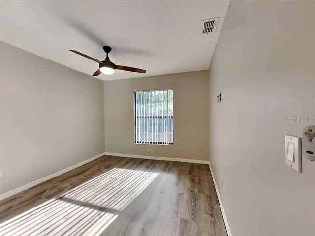 a view of a room with a ceiling fan and wooden floor