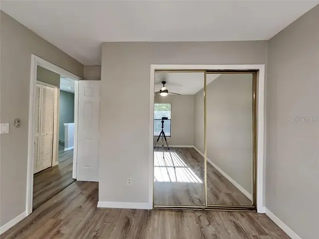 a view of empty room with wooden floor and fan