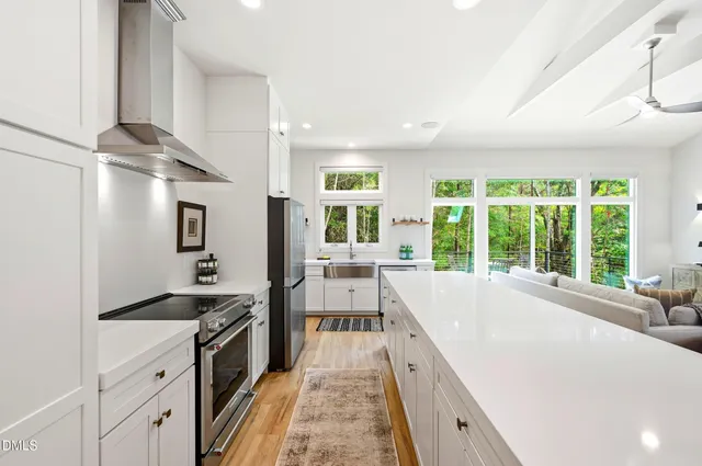 a large kitchen with kitchen island a large window cabinets and stainless steel appliances