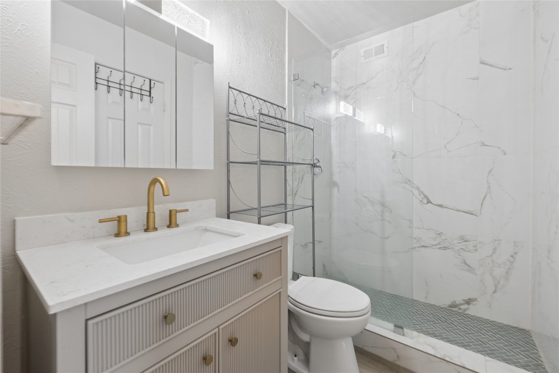 820 Sahara Avenue, Unit B Austin, TX 78745 - Photo 3 of 29 Bathroom with vanity, a marble finish shower, a textured wall, and marble look tiles
