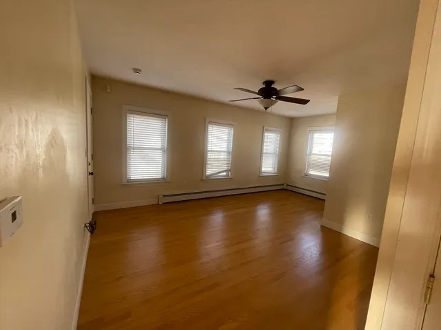 a view of empty room with wooden floor and fan