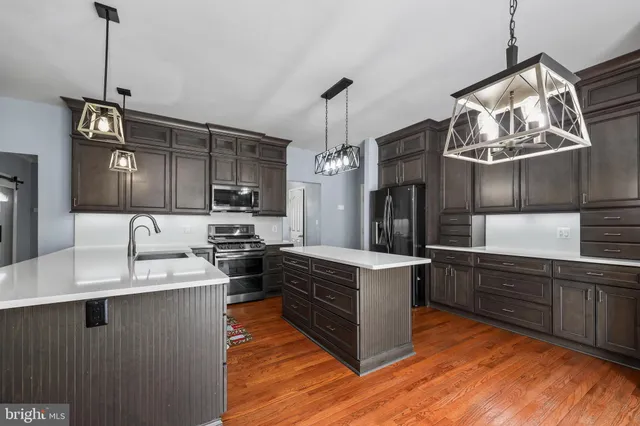 a kitchen with stainless steel appliances granite countertop a sink a stove and a wooden floor