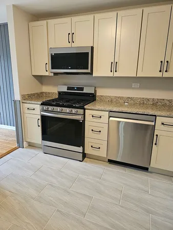 a kitchen with stainless steel appliances granite countertop a stove a microwave and a white cabinets