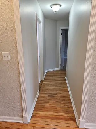 a view of a hallway with wooden floor and stairs