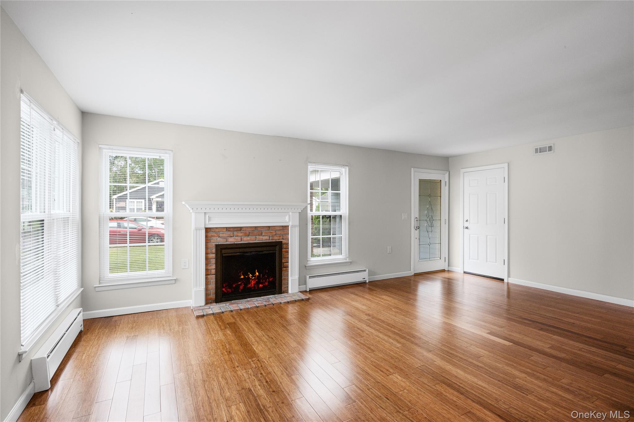 220 Belfast Lane Ridge, NY 11961 - Photo 12 of 44 an empty room with wooden floor fireplace and windows