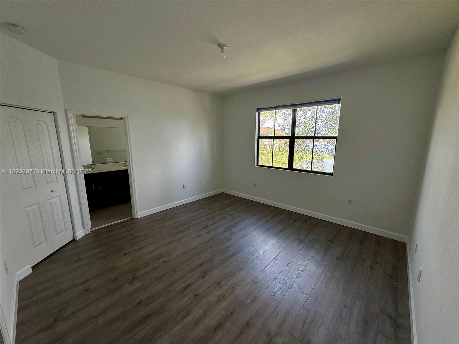 1075 Northwest 33rd Manor Pompano Beach, FL 33064 - Photo 11 of 27 an empty room with wooden floor and windows