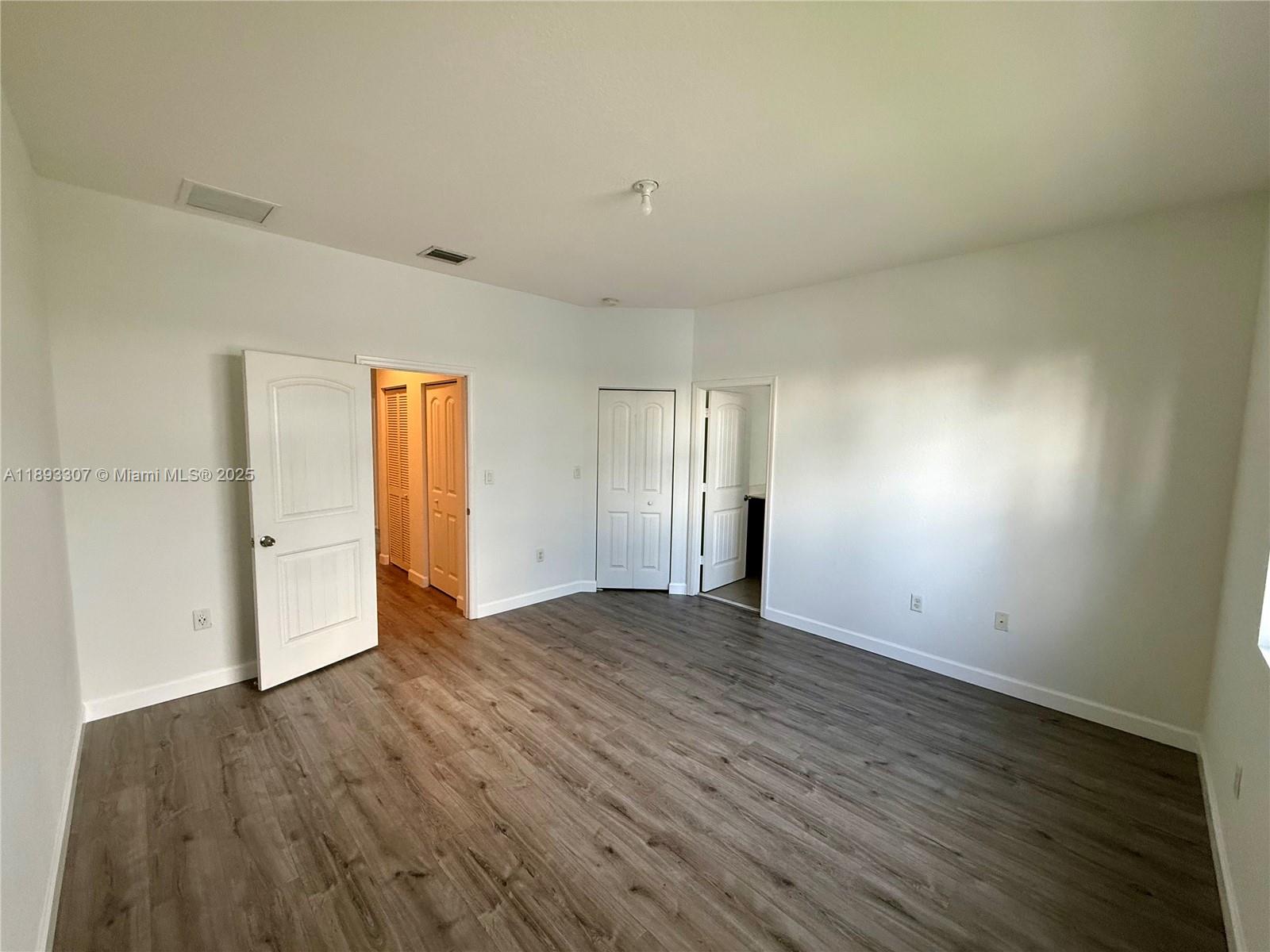 1075 Northwest 33rd Manor Pompano Beach, FL 33064 - Photo 12 of 27 an empty room with wooden floor and windows