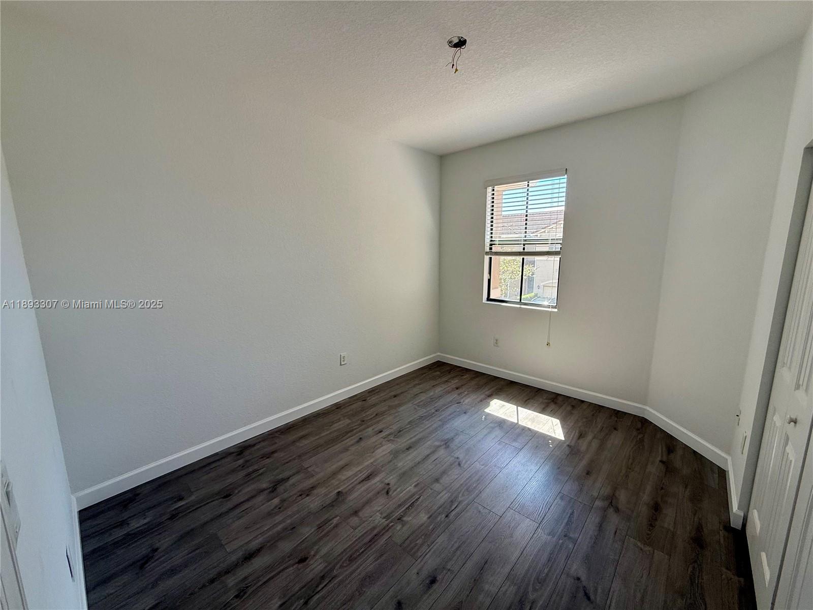 1075 Northwest 33rd Manor Pompano Beach, FL 33064 - Photo 14 of 27 an empty room with wooden floor and windows
