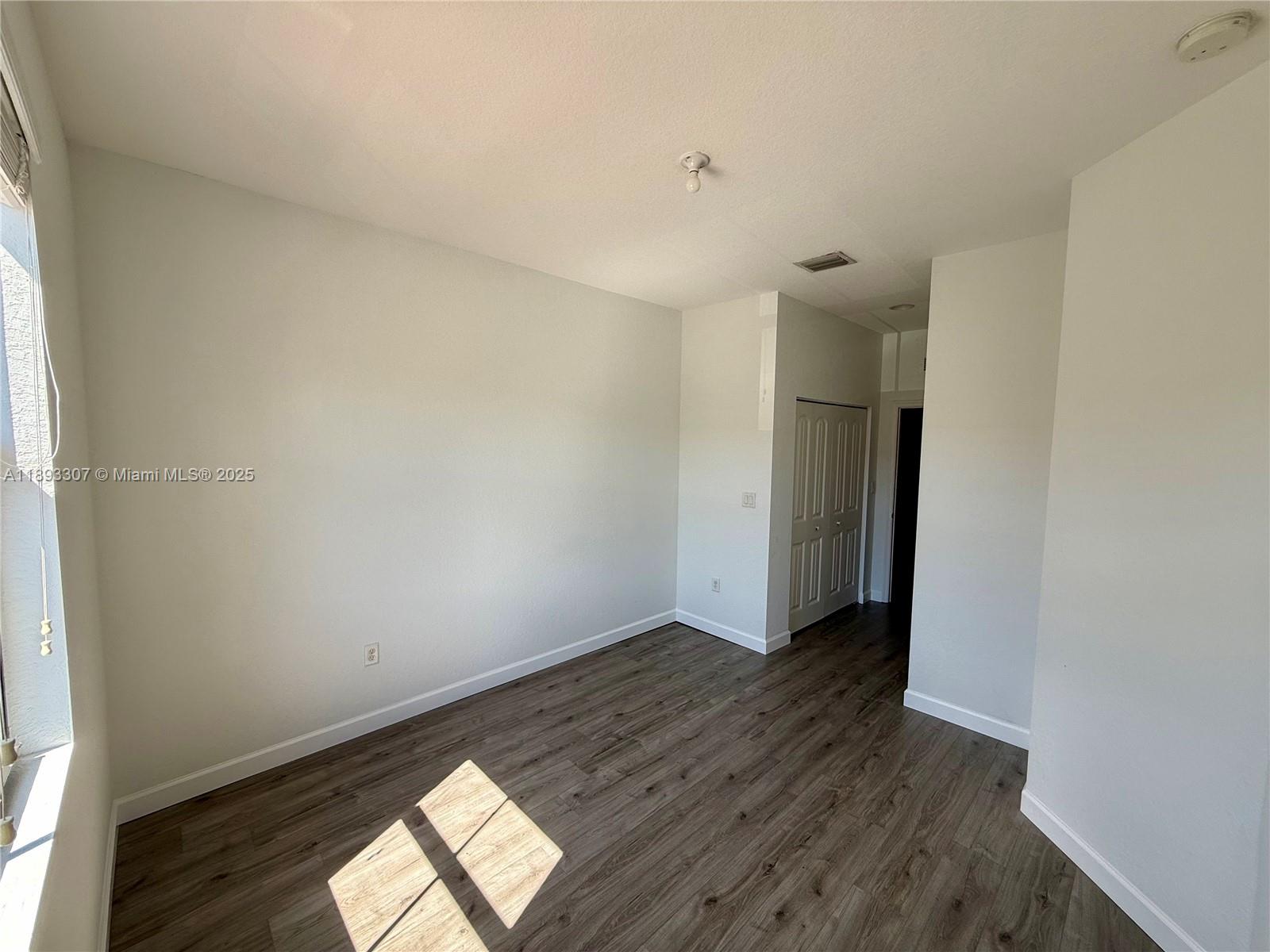 1075 Northwest 33rd Manor Pompano Beach, FL 33064 - Photo 18 of 27 an empty room with wooden floor and windows