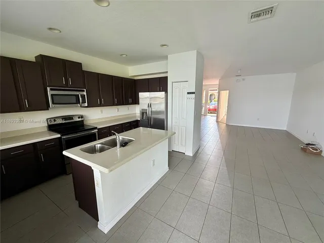 a kitchen with kitchen island granite countertop a sink stove and refrigerator