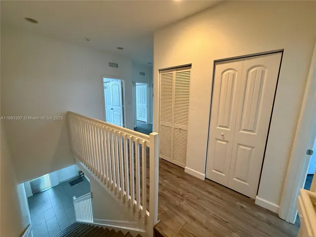 a view of a hallway with wooden floor and staircase