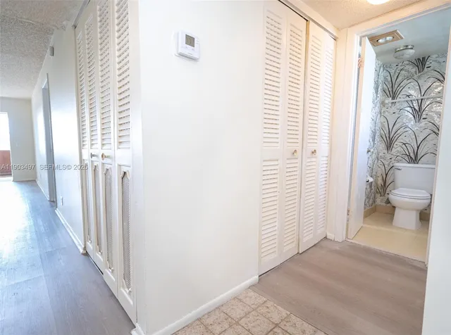 a view of a hallway with wooden floor and a bathroom