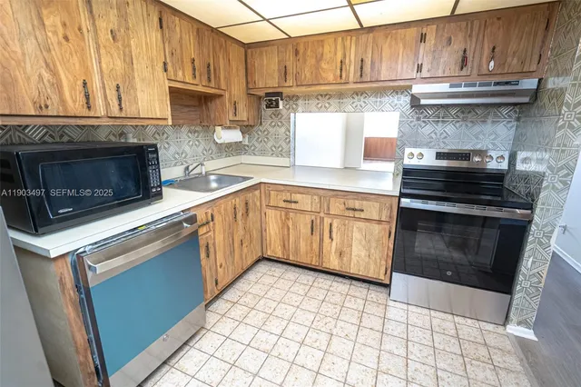 a kitchen with granite countertop a stove top oven microwave and cabinets