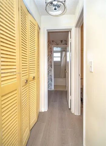 a view of a hallway with wooden floor and a bathroom
