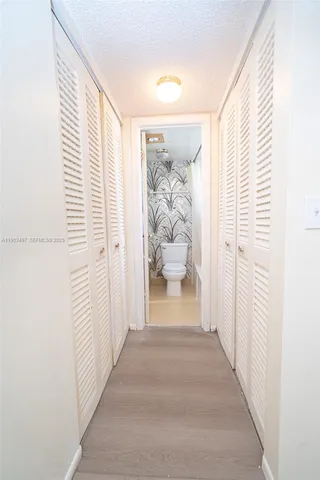 a view of a hallway with wooden floor and closet
