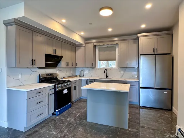 a large kitchen with stainless steel appliances granite countertop a sink a stove a refrigerator and a microwave