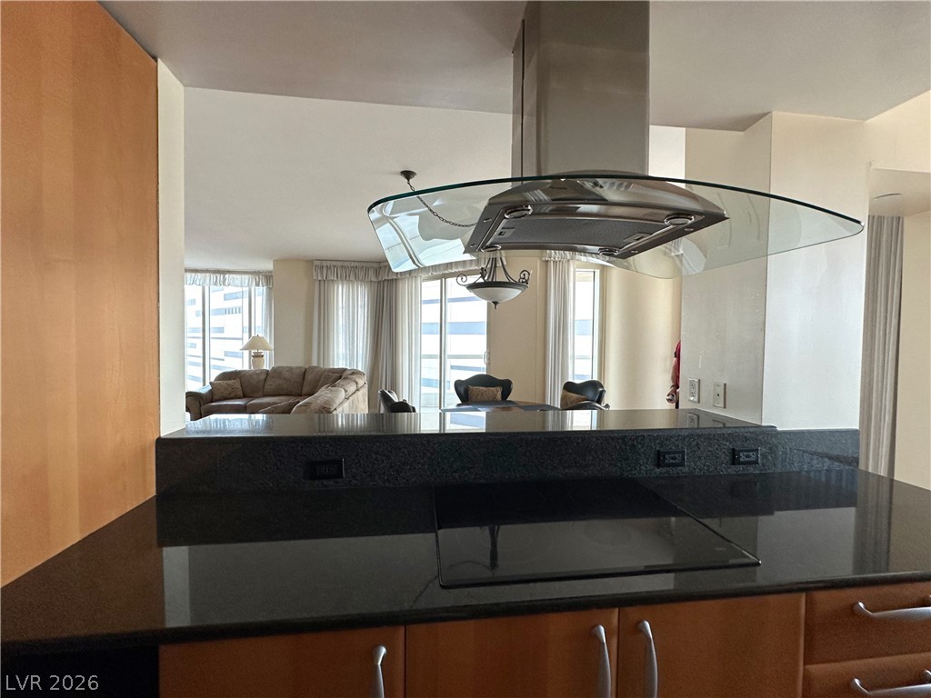 2747 Paradise Road, Unit 1706 Las Vegas, NV 89109 - Photo 12 of 35 An open-concept kitchen with sleek black granite counters and a glass range hood flows into a bright living space.