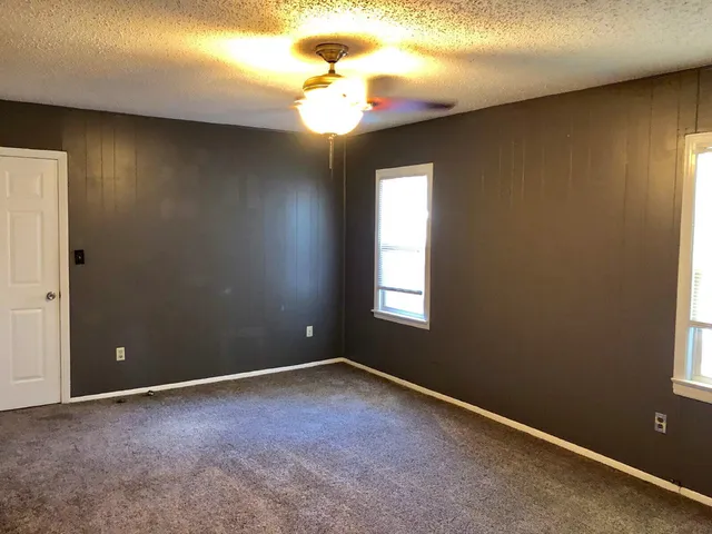 an empty room with windows and fan