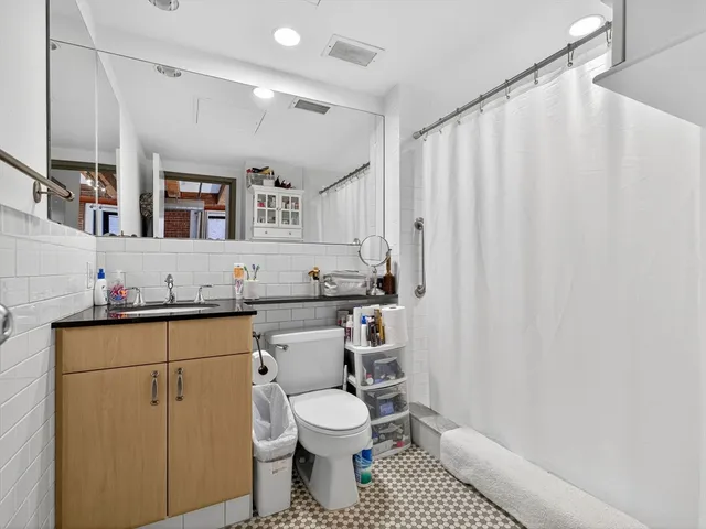 a bathroom with a granite countertop sink mirror vanity and toilet