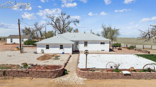 a view of a white house next to a yard with big trees