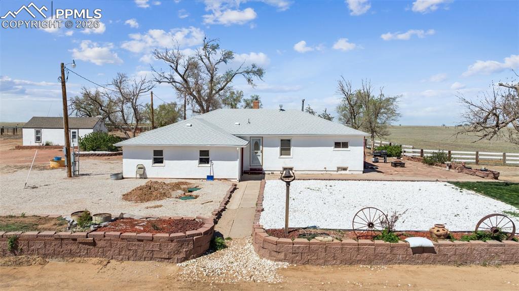a view of a white house next to a yard with big trees