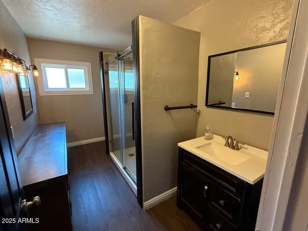 a bathroom with a sink a mirror a vanity and a shower
