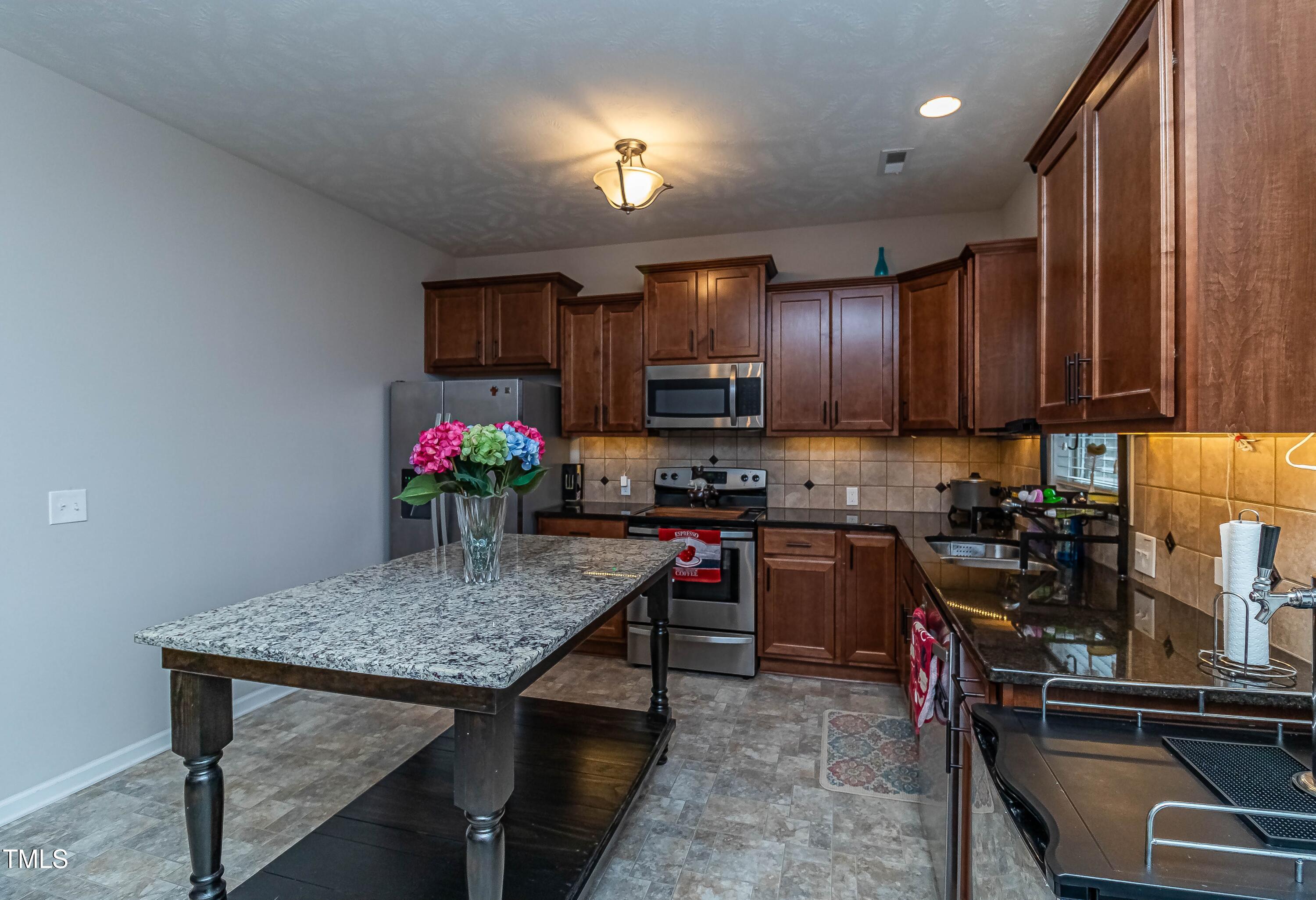 1852 Alderman Mill Road Dunn, NC 28334 - Photo 12 of 36 a kitchen with kitchen island granite countertop a stove top oven microwave and cabinets