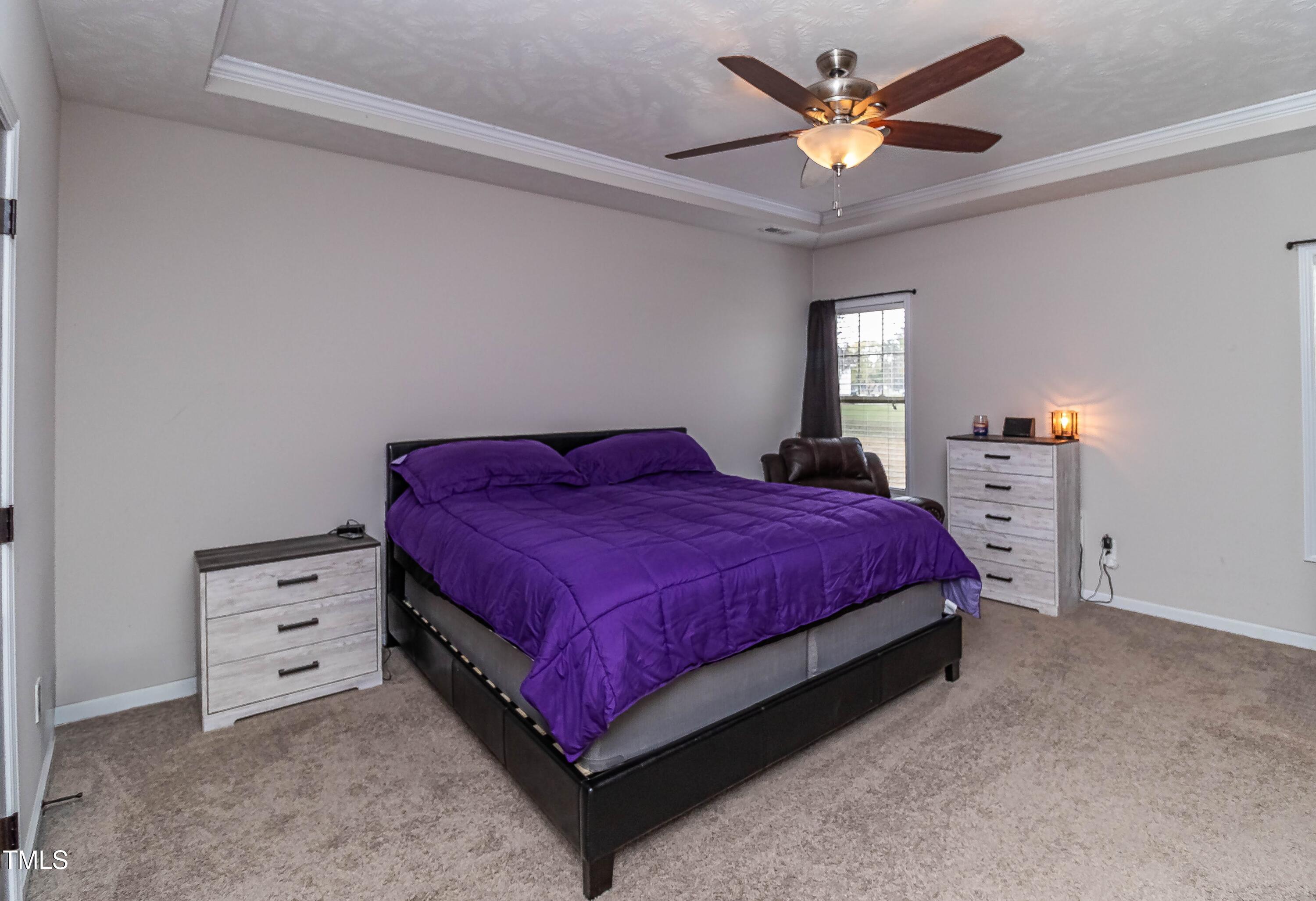 1852 Alderman Mill Road Dunn, NC 28334 - Photo 27 of 36 a spacious bedroom with a bed a window and a chandelier