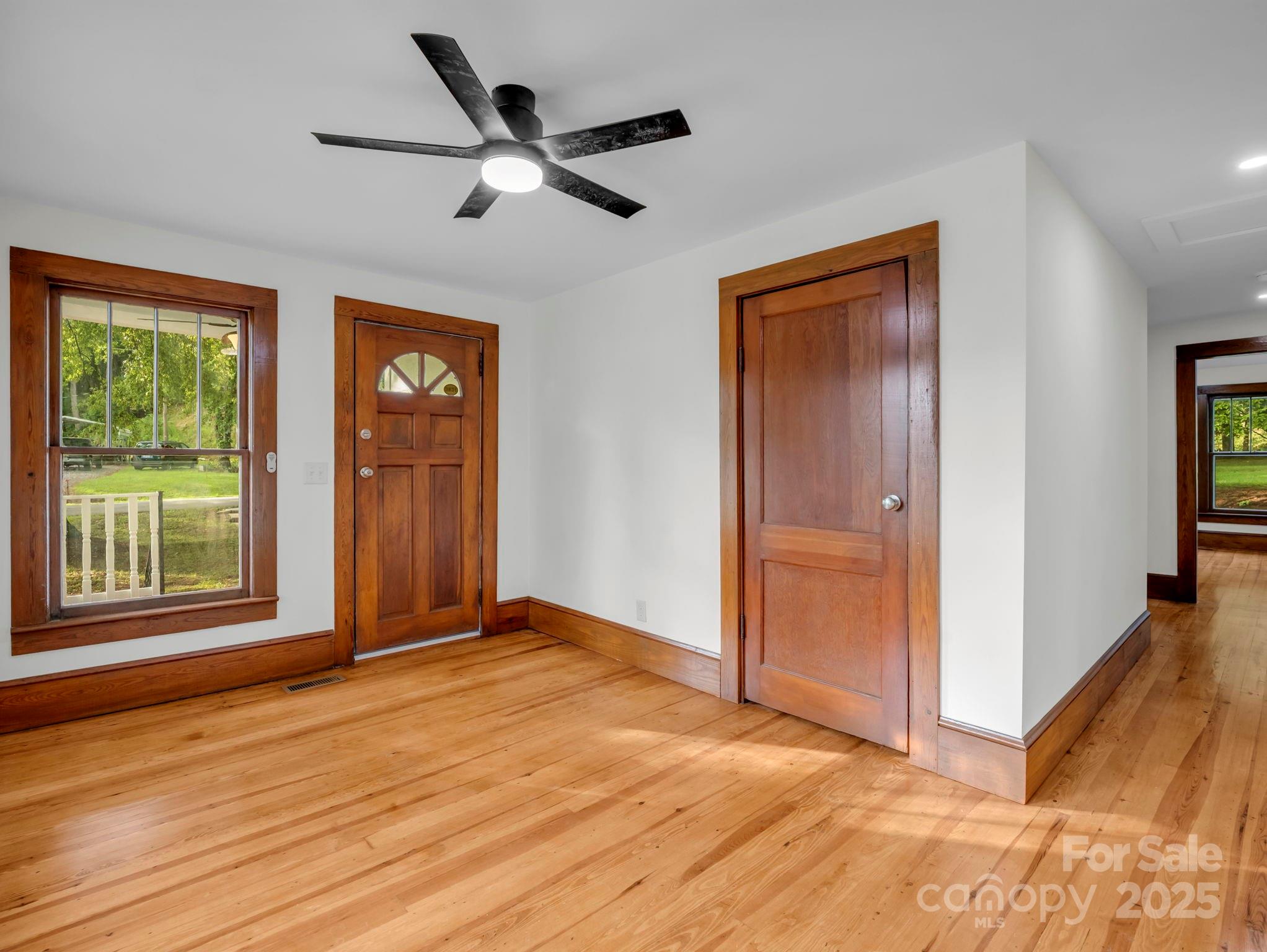 339 Flack Road Forest City, NC 28043 - Photo 9 of 32 an empty room with wooden floor a ceiling fan and windows