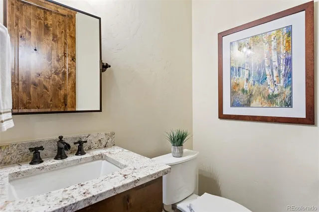 a bathroom with a granite countertop sink a mirror and a toilet