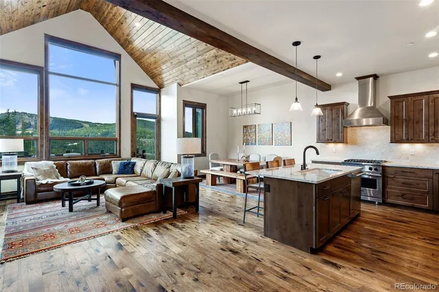 a large living room with stainless steel appliances granite countertop a stove a sink dishwasher and wooden cabinets with wooden floor