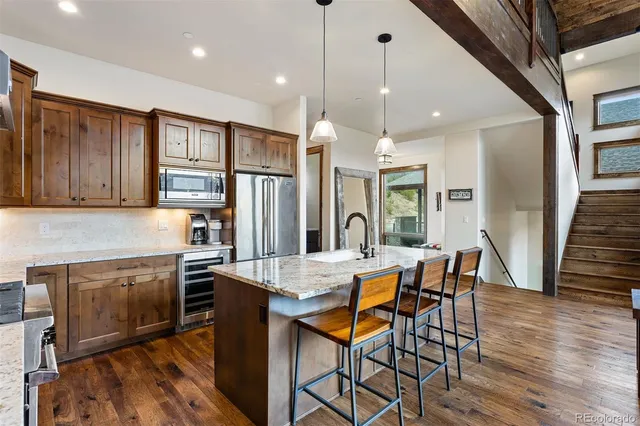 a kitchen with stainless steel appliances granite countertop a stove top oven a sink dishwasher a dining table and chairs with wooden floor