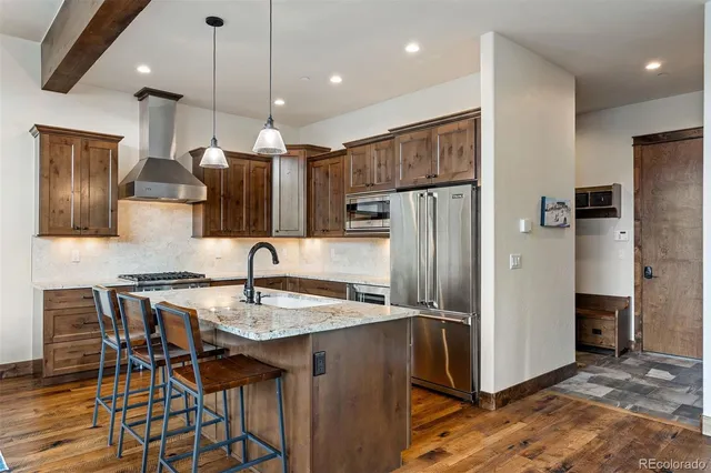 a kitchen with stainless steel appliances granite countertop a refrigerator a sink a stove a dining table and chairs