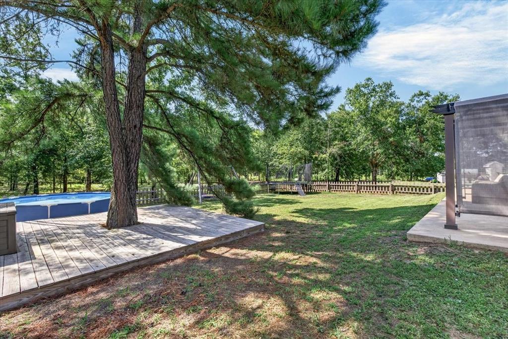531 VZ County Road Eustace, TX 75124 - Photo 22 of 35 Expansive backyard featuring a large tree, above-ground pool with surrounding wood decking, concrete patio, and fenced perimeter