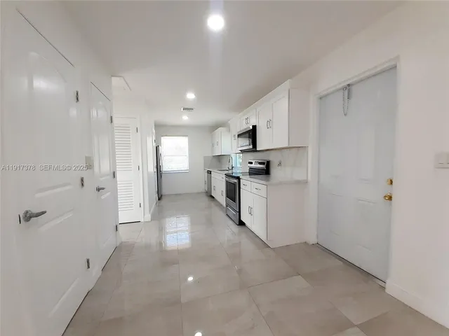 a large white kitchen with a refrigerator a stove top oven a sink and dishwasher
