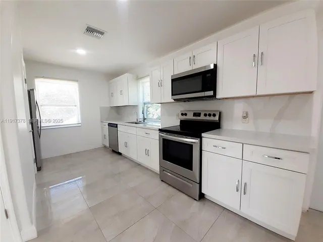 a kitchen with white cabinets stainless steel appliances and sink