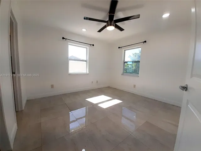 en empty room with windows and ceiling fan